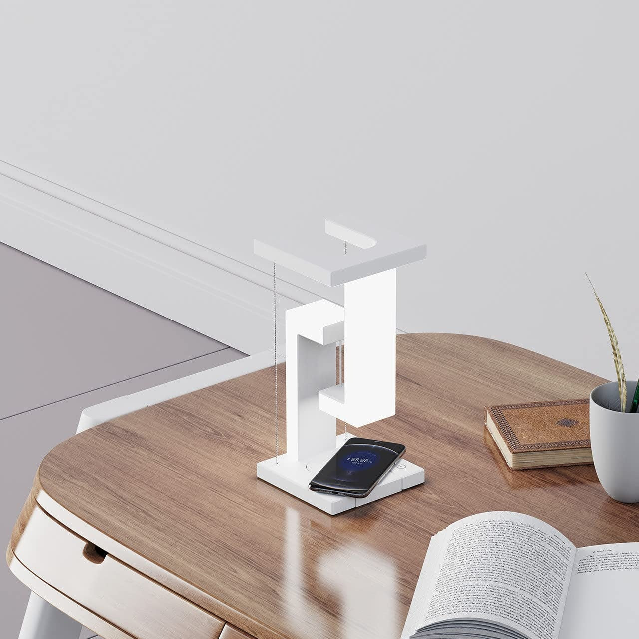 White desk lamp on a wooden desk with a phone and open book