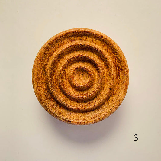 Wooden object with concentric circular patterns on a beige background